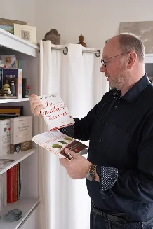 Photo de geoffrey au bureau dans sa bibliotheque avec des livres a la main la meilleure vie jk rolling transmettre