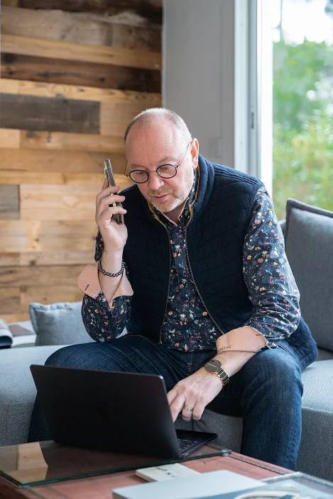 Photo de geoffrey au telephone sur le canape en interagissant avec son macbook